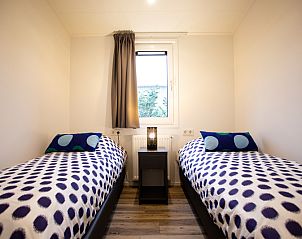 Cozy bedroom in Nature Lodge for 4 people, Berkhout, North Holland, with comfortable beds and a peaceful view.