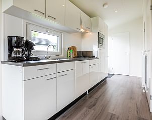 Modern kitchen in holiday home Rialto 5 persons, Berkhout, North Holland, with sleek white cabinets and wooden floor.