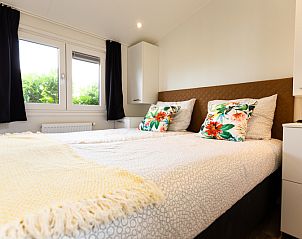 Cozy bedroom in Rialto MAX 6-person vacation home, Berkhout, North Holland, with comfortable bed and view of green surroundings.