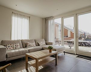 Gezellige woonkamer van vakantiehuis Waterfront in Uitgeest, Noord-Holland, met comfortabele bank en uitzicht op terras.