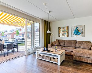Gezellige woonkamer van vakantiehuis Assum Great in Uitgeest, Noord-Holland, met comfortabel interieur en terraszicht.