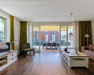 Gezellige woonkamer in vakantiehuis Assum Great, Uitgeest, Noord-Holland met uitzicht op terras en moderne inrichting.