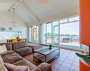 Penthouse vakantiehuis in Uitgeest, Noord-Holland met ruime woonkamer en terras met uitzicht op het meer, ideaal voor ontspanning.