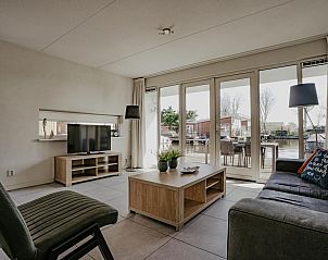 Lichte woonkamer van vakantiehuis Dorregeest in Uitgeest, Noord-Holland met uitzicht op terras en water.