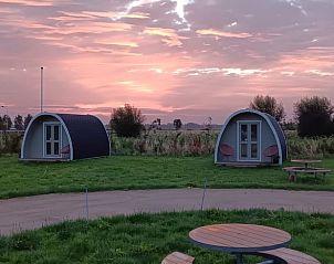 Twee vakantiehuisjes bij zonsondergang in Huisje in Zuid-Scharwoude, Noord-Holland, omgeven door een serene omgeving.