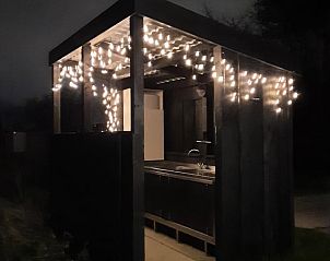 Sfeervolle buitenkeuken bij nacht in Huisje in Zuid-Scharwoude, een vakantiehuis in Noord-Holland, met gezellige verlichting.