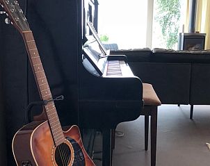 Gitaar naast piano in Vakantiehuis in Broek in Waterland, Amsterdam eo, Noord-Holland, met rustieke inrichting.