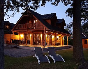 Huisje in Den Ham, een sfeervol vakantiehuis in Twente, Overijssel, met een uitnodigend terras en warme verlichting bij zonsondergang.