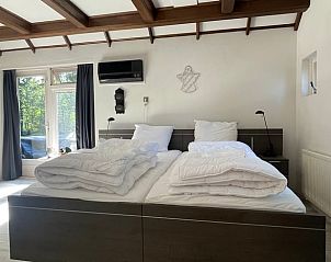 Ruime slaapkamer in Vakantiehuis in Den Ham, met groot raam en veel licht.