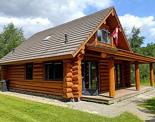 Rustiek vakantiehuis in Den Ham, Twente, Overijssel met houten veranda en groene omgeving, ideaal voor een ontspannen verblijf in de natuur.