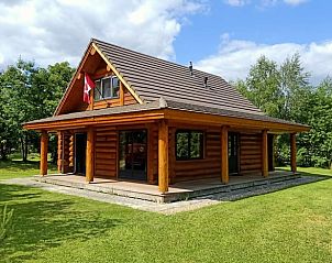 Rustiek vakantiehuis in Den Ham, Twente, Overijssel met houten veranda en groene omgeving, ideaal voor een ontspannen verblijf in de natuur.