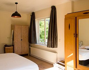Attraktives Schlafzimmer im Ferienhaus in De Lutte, Twente, mit Holzmbeln und Blick auf die grne Umgebung von Overijssel.