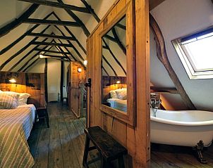 Gezellige slaapkamer met houten balken en bad in Huisje in Hezingen, Twente, Overijssel.