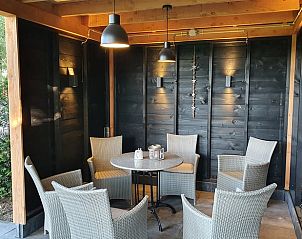 Overdekt terras met zitgelegenheid in vakantiehuis Hezingen, Twente, voor ontspanning.