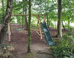 Speeltuin met schommel en glijbaan in de tuin van vakantiehuis Hezingen, Twente.