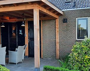 Overdekte veranda met zitplaatsen bij vakantiehuis Hezingen, Twente, voor buitenleven.