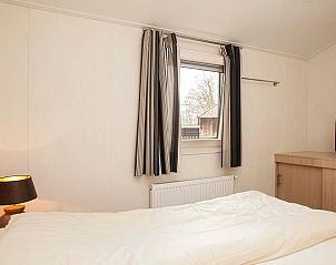 Slaapkamer met raam en gordijnen in vakantiehuisje in Hezingen, Twente, Overijssel.