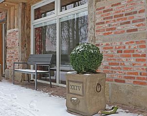 Sneeuw bedekt de veranda van Huisje in Hezingen, vakantieaccommodatie in Twente, Overijssel.