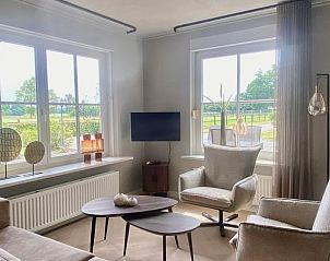 Lichte woonkamer in Huisje in Rijssen, vakantieaccommodatie in Twente, Overijssel, met uitzicht op de groene omgeving.