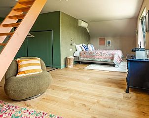 Open ruimte in Vakantiehuis in Rijssen, Twente met trap naar boven en comfortabele zithoek.