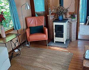 Stijlvolle woonkamer in vakantiehuis in Hengelo, Twente met houtkachel en comfortabele stoel.