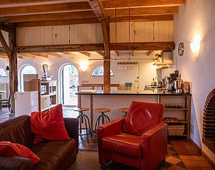 Comfortabele zithoek in vakantiehuisje Hengelo, Twente, met open haard en houten balken in Overijssel.