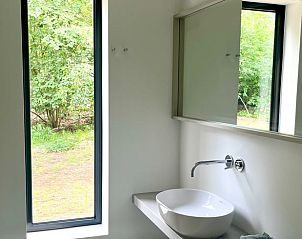 Moderne badkamer in Huisje in Haaksbergen, vakantiehuis in Twente, met wastafel en groot raam met uitzicht.