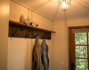 Gezellige entree van Huisje in Diepenheim, vakantiehuis in Twente, Overijssel, met houten kapstok en sfeervolle verlichting.