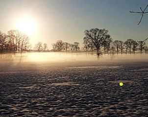 Ontdek de serene winterlandschappen rondom Vakantiehuisje in Diepenheim, Twente, Overijssel, omgeven door een mistige zonsopgang.