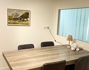 Eetkamer in Vakantiehuisje in Enschede, Twente, met houten tafel en schilderij aan de muur voor gezellige maaltijden.