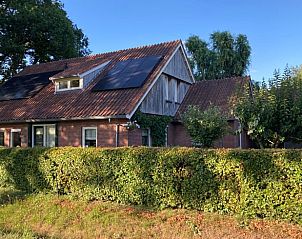 Zonnige gevel van Vakantiehuis in Oldenzaal, Twente, met zonnepanelen en groene heg voor duurzame charme.