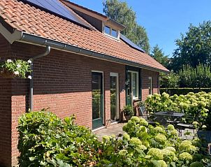 Zijaanzicht van Vakantiehuis in Oldenzaal, Twente, met zonnig terras en groene omgeving voor een ontspannen verblijf.