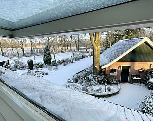 Uitzicht op besneeuwde tuin vanuit Huisje in Oldenzaal vakantiehuis in Twente, Overijssel.