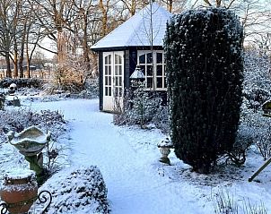 Besneeuwde tuin met prieel bij Huisje in Oldenzaal vakantiehuis in Twente, Overijssel.
