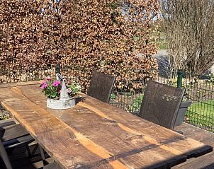 Gezellig terras bij vakantiehuis in Markelo, Twente, met houten tafel en bloemen.