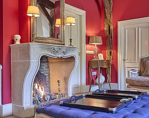 Gezellige woonkamer van vakantiehuis Erve Het Klaashuis in Deurningen, Twente, met sfeervolle open haard en warme inrichting.