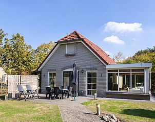 Vuurvlinder met Serre 4, een charmante bungalow in Hoge Hexel, Twente, biedt een uitnodigend terras met uitzicht op de groene omgeving.