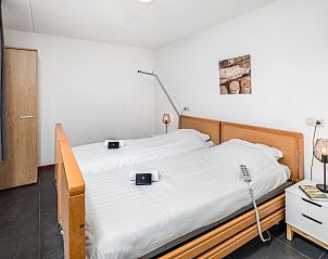 Luxurises Badezimmer von Twentse Hoeve 14, einem Bungalow in Hoge Hexel, Twente, Overijssel, mit Doppelwaschbecken und gerumiger Badewanne mit Blick auf die Natur.