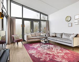 Moderne Sitzecke im Ferienhaus Sallandse Heuvelrug 8C, Twente, mit buntem Teppich und viel Tageslicht.