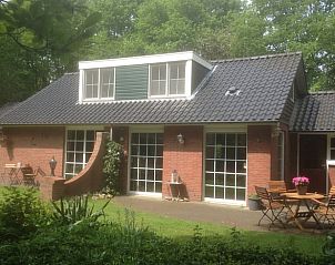 Charmant vakantiehuisje in Holten, Overijssel, omgeven door groen met een uitnodigend terras voor ontspanning in de natuur.