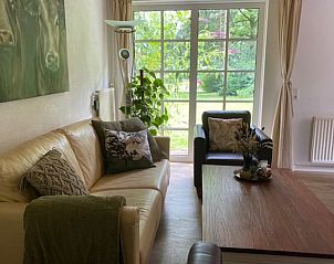 Gezellige woonkamer in Vakantiehuisje in Holten, Overijssel met uitzicht op de groene tuin. Ideaal voor een ontspannen verblijf in Salland.