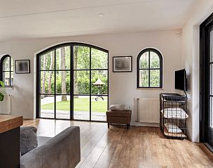 Lichte woonkamer van Huisje in Holten, vakantiehuis in Salland, Overijssel met uitzicht op groene tuin door grote ramen.