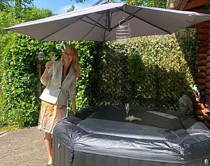 Geniet van ontspanning in de tuin van Vakantiehuisje in Holten, gelegen in het groene Salland, Overijssel, met een luxe jacuzzi onder een parasol.