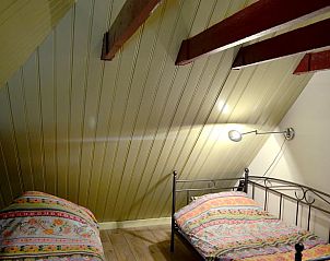 Slaapkamer met houten balken in vakantiehuis in Wijhe, Salland, perfect voor een ontspannen verblijf.