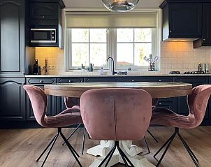 Gemtliche Kche in Cottage in Hellendoorn, Ferienhaus in Hellendoorn, Overijssel mit Holztisch und rosa Sthlen.