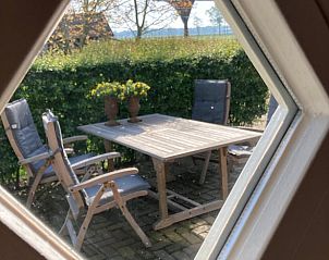 Gezellige buitenruimte van vakantiehuis in Hellendoorn gezien door raam, perfect voor ontspanning in Salland, Overijssel.