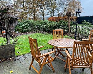 Relax on the terrace of Cottage in Ommen, vacation home in Vechtstreek, Overijssel, overlooking the green garden and rural surroundings.