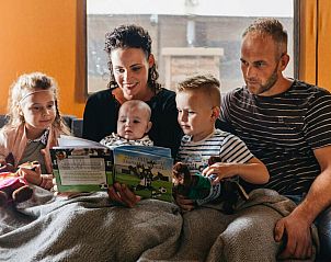 Gezin leest samen in de knusse woonkamer van Vechtglamping Lodge, Beerze.