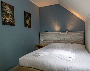 Gezellige slaapkamer in Vakantiehuis 6-persoons, Dalfsen, met kunst aan de muur en sfeervolle verlichting.