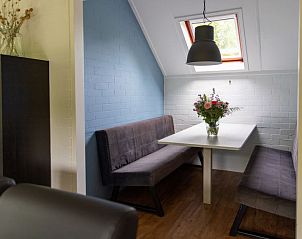 Knusse eetruimte in Vakantiehuis 6-persoons, Dalfsen, met bankjes en bloemen op tafel.